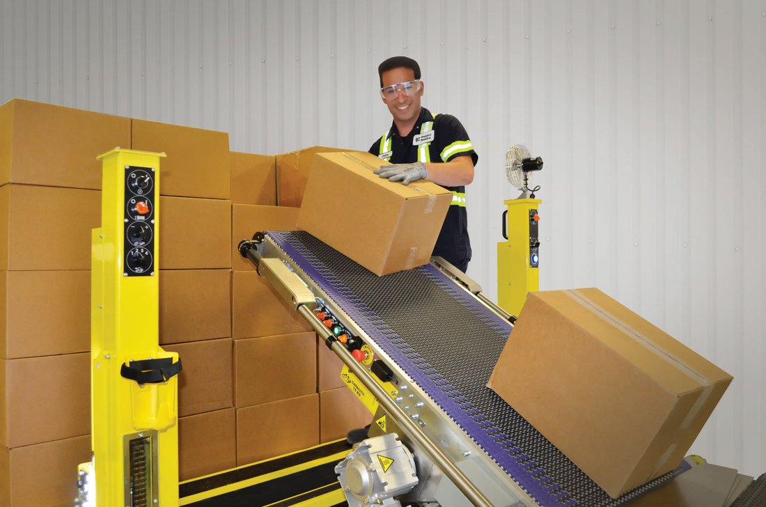 Operator unloading cartons from a trailer onto a Destuff-it conveyor