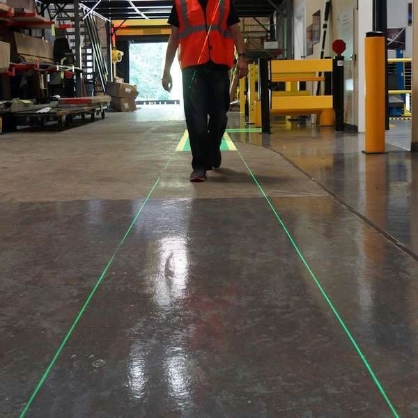Worker walking between two thin green laser lines that mark a walkway