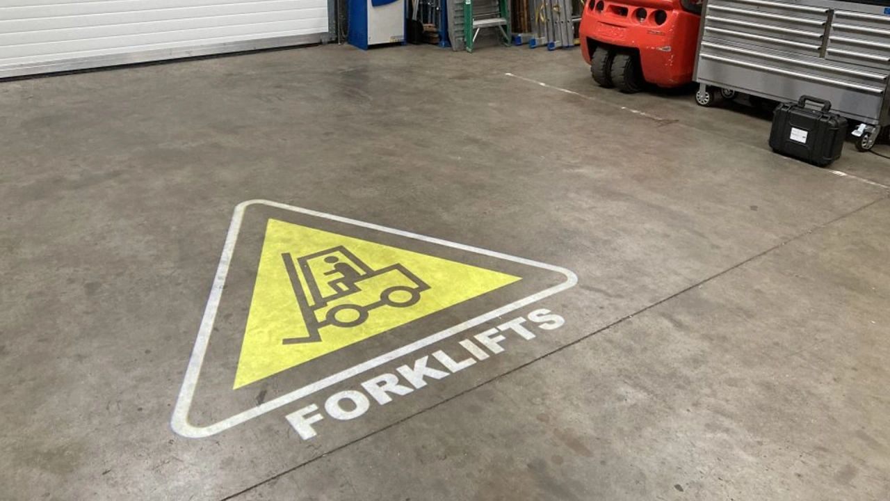 Projected forklift warning sign on a plant floor