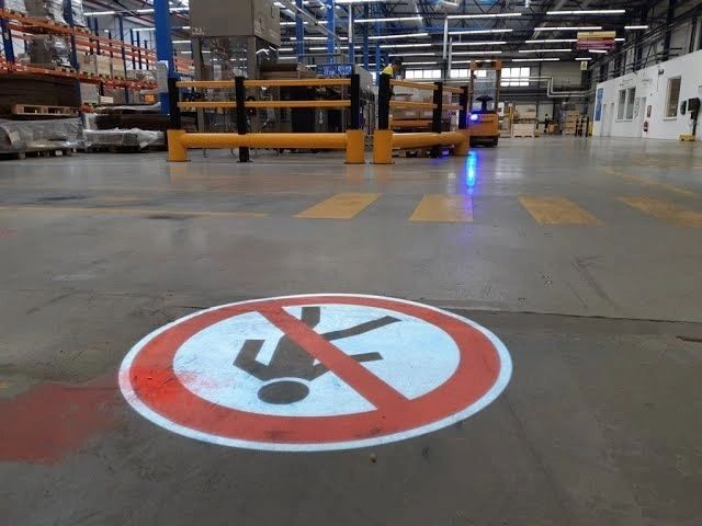 Forklift with a blue warning spot behind a projected no-pedestrians sign